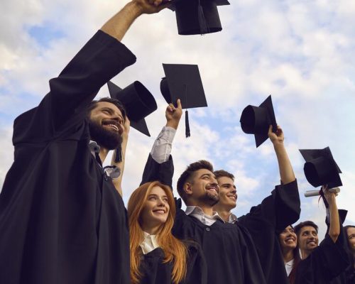 millennial-students-celebrating-graduation-ceremony-throwing-their-caps-up-outdoors-copy-space-text-young-people-215448743